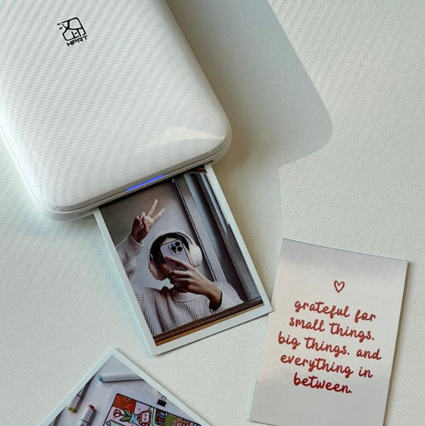 Small printer with printed photos and a card on a white surface