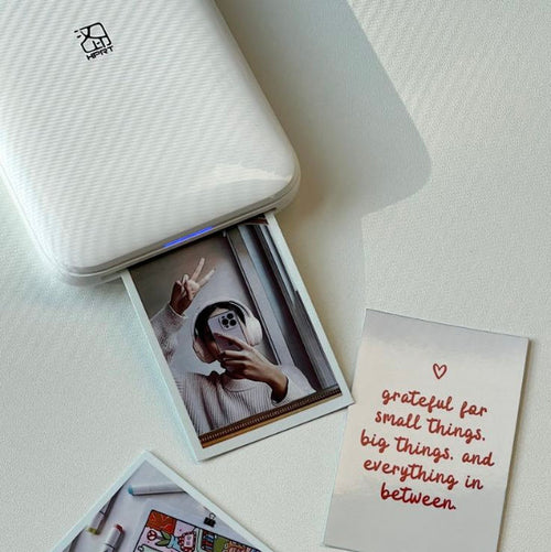 Small printer with printed photos and a card on a white surface
