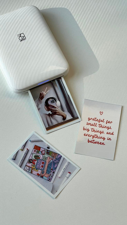 Small printer with printed photos and a card on a white surface